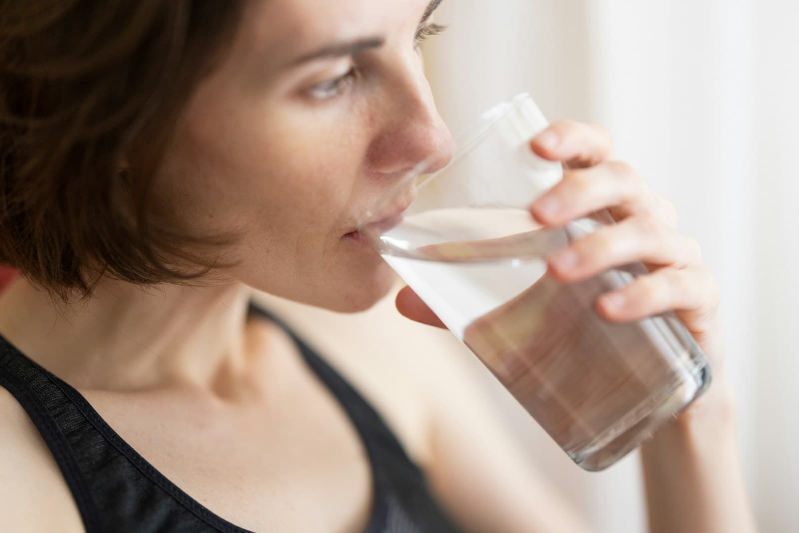 黒タンクトップで水を飲む女性